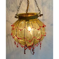 a chandelier hanging from a chain with red beads on it's sides