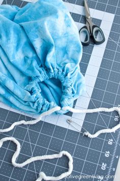 a pair of scissors sitting on top of a piece of cloth next to some thread