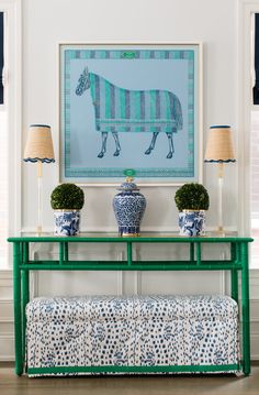 a green console table with two blue and white vases on it next to a painting