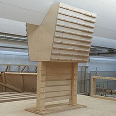 a large wooden structure sitting in the middle of a room with lots of wood planks