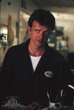 a man sitting at a table in front of a cup with pens and markers on it