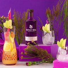 a bottle of whitley's mellows gin on a table with flowers and ice