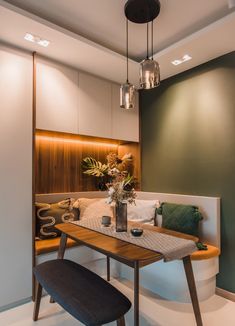 a table and bench in a room with lights on the wall above it, along with other furniture