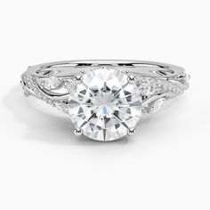 a white gold engagement ring with an intricate band and a round center stone surrounded by diamonds