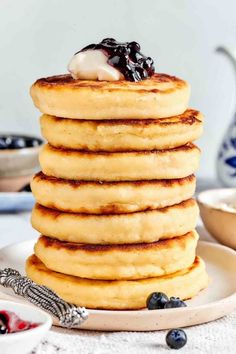 a stack of pancakes with blueberries and whipped cream on top, sitting on a plate