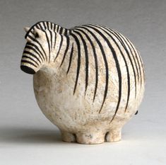 a ceramic zebra figurine sitting on top of a white table next to a gray wall