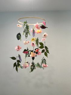 a mobile with flowers hanging from it's side on a wall in a room