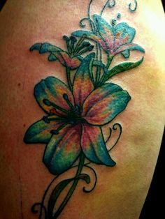 a colorful flower tattoo on the back of a woman's shoulder