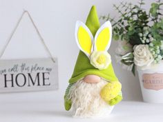 a gnome with a green hat and white beard is sitting next to a potted plant