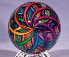 a multicolored glass ball sitting on top of a metal stand with rings around it