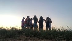 a group of people standing on top of a grass covered field