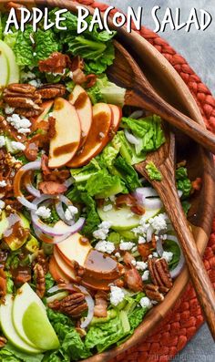 a salad with apples, lettuce and pecans in a wooden bowl on a table