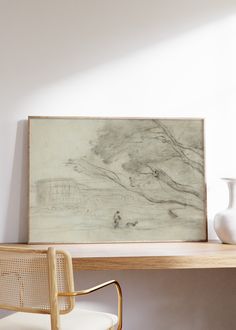 a white vase sitting on top of a wooden table next to a painting and chair