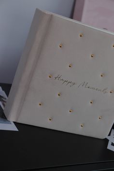 a white card with gold studs on it sitting on a table next to photos