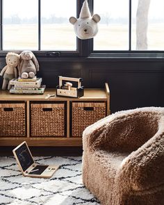 a teddy bear sitting on top of a wooden table next to a basket filled with books