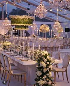 a long table is set up with white flowers and candles for an elegant wedding reception