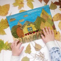 a child is making a painting with leaves on the ground and in front of it