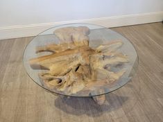 a glass table with driftwood pieces on the top and bottom, sitting on a wood floor