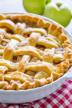 an apple pie sitting on top of a red and white checkered table cloth