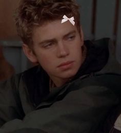 a young man with a bow on his head looking at the camera while sitting down