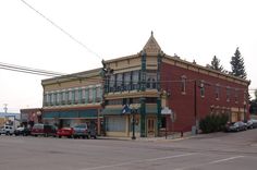 an old red brick building on the corner of a street with cars parked in front