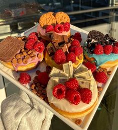 there are many different desserts on the plate and one has chocolate, raspberries, donuts, and other pastries