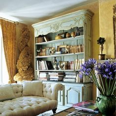 a living room filled with lots of furniture and bookshelf next to a window