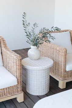 two wicker chairs sitting next to each other on top of a wooden floor covered in white pillows