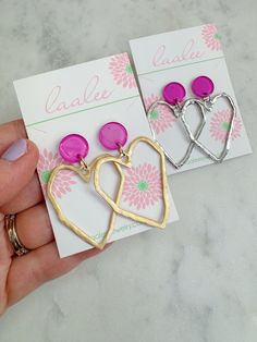 "Beautiful gold and silver heart earrings with a pink acrylic round stud measuring approximately 2\". Giftbox included." Trendy Round Earrings For Valentine's Day, Trendy Round Valentine's Day Earrings, Pink Metal Heart Earrings For Pierced Ears, Pink Heart Earrings For Pierced Ears, Trendy Heart Earrings For Valentine's Day Anniversary, Pink Nickel-free Heart Earrings For Valentine's Day, Pink Round Earrings For Valentine's Day, Nickel Free Round Heart Earrings For Valentine's Day, Nickel-free Round Heart Earrings For Valentine's Day