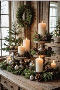 candles are arranged on top of a table with pine cones and evergreen branches in the center