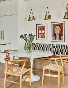 a dining room table with four chairs and pictures on the wall above it in an apartment