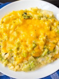 a white plate topped with broccoli and cheese casserole on top of a blue table cloth