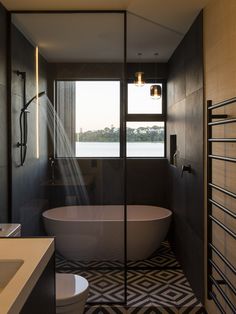 a bathroom with a bathtub, sink and toilet next to a window that looks out onto the water