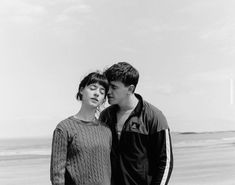 a man and woman standing next to each other on the beach