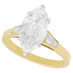 a pear shaped diamond ring with two baguets in yellow gold and white diamonds