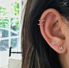 a woman's ear with three different piercings on top of her head and one behind the ear