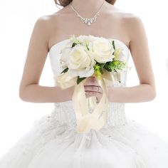 a woman in a white wedding dress holding a bouquet of flowers and wearing a yellow ribbon around her neck