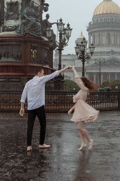 a man and woman dancing in the rain with their arms stretched out to each other