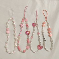 four necklaces with hearts, pearls and beads on a white sheet that says happy valentine's day