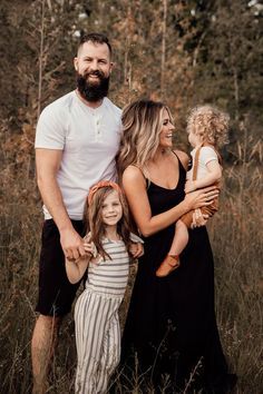 a man and woman with two children standing in tall grass