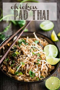 chicken pad thai noodles in a black bowl with chopsticks and lime wedges