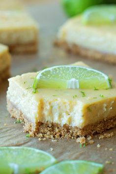 a slice of key lime cheesecake on top of a cutting board with limes around it