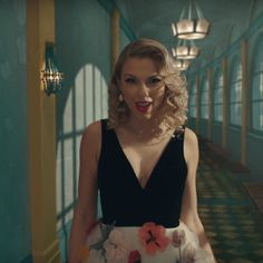 a woman in a black and white dress with flowers on her skirt standing in a hallway