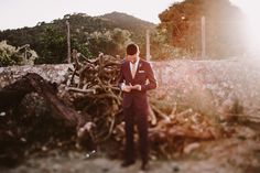 a man in a suit standing next to a pile of wood