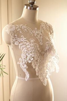 a mannequin with white lace on it's back and shoulder, in front of a door