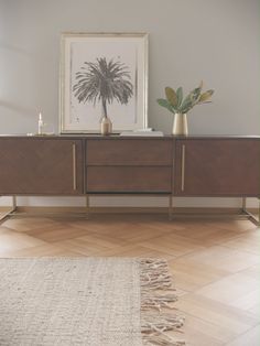 a wooden sideboard with two vases and a painting on it's wall