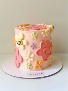 a pink cake decorated with flowers and smiley faces