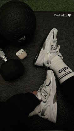 someone wearing white sneakers and black leggings standing next to a large ball with the word on it