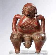 an old figurine sitting on top of a glass stand with its legs crossed