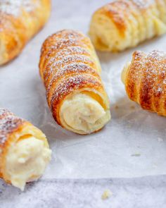 croissants with powdered sugar on them sitting on top of wax paper